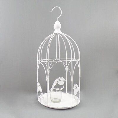 a white birdcage with two birds in it on a table next to a gray background