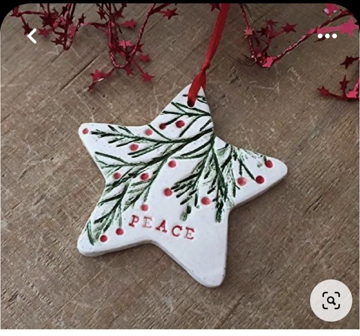 a ceramic christmas ornament hanging from a red ribbon on top of a wooden table