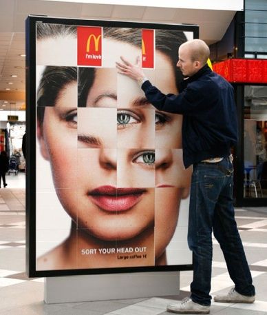 a man standing next to a giant advertisement for mcdonald's