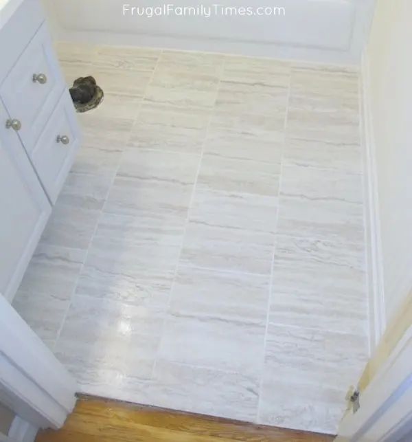 an empty bathroom with white cabinets and tile flooring