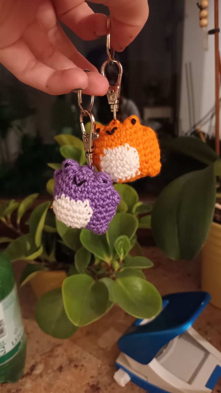 two crocheted keychains hanging from a plant