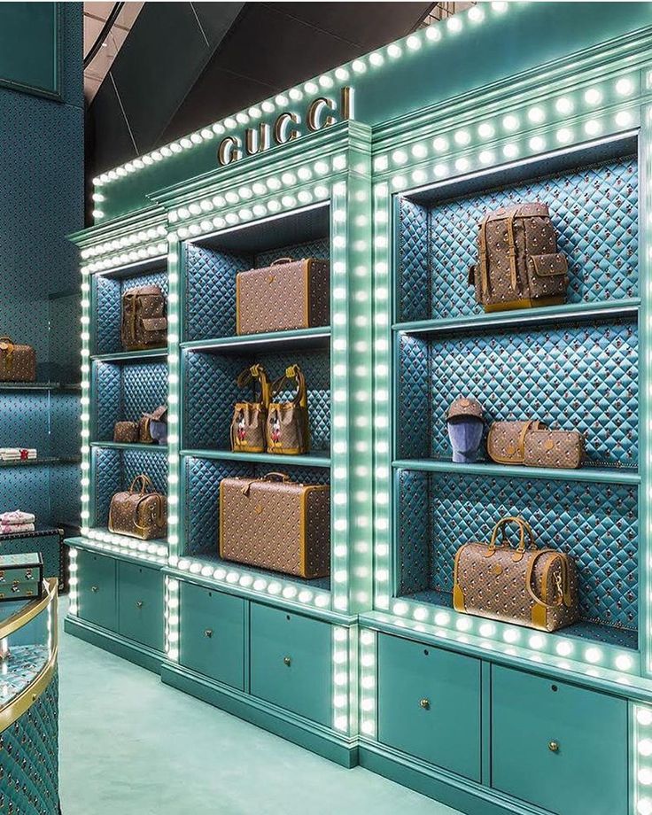 the interior of a gucci store with blue walls and shelves filled with purses