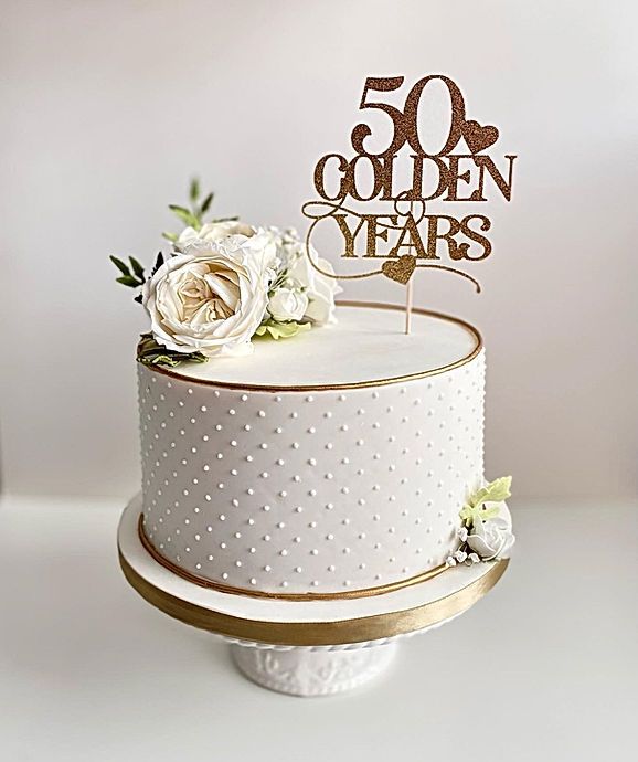 a white cake with gold lettering and flowers on top