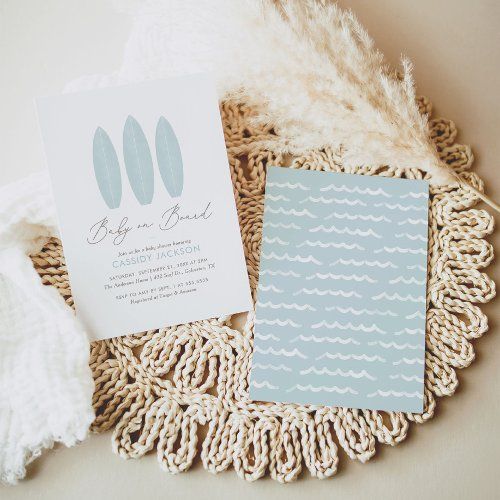 the wedding stationery is laid out on top of a doily with some feathers