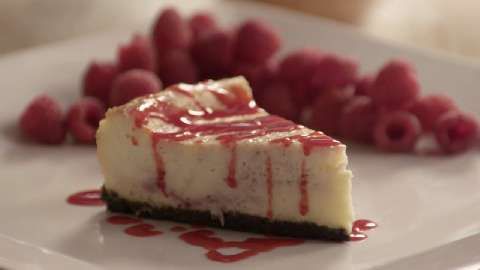 a piece of cheesecake on a plate with raspberries