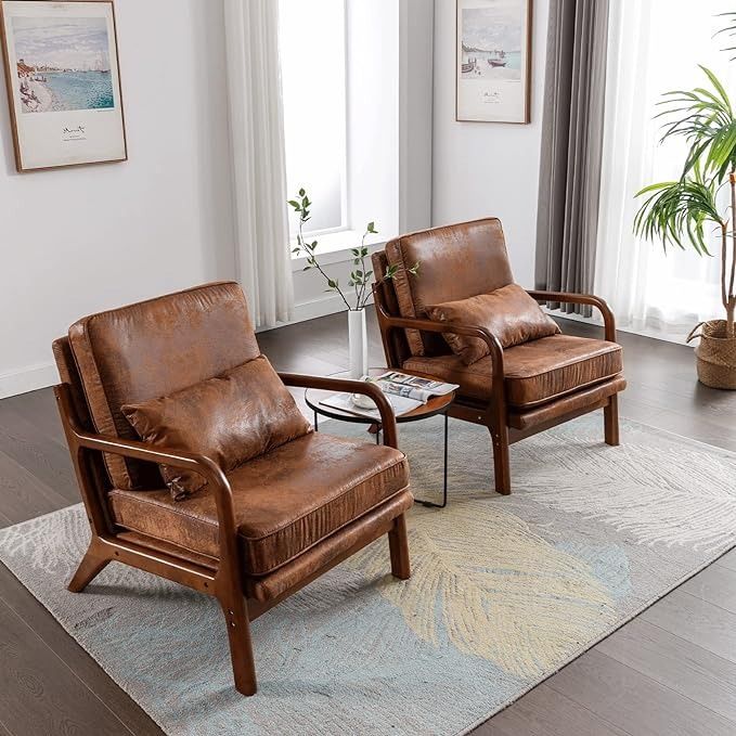 two brown leather chairs sitting on top of a rug