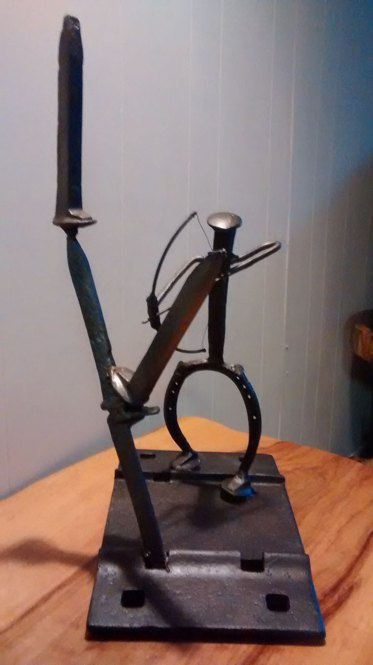 a metal sculpture with a knife sticking out of it's back end on top of a wooden table