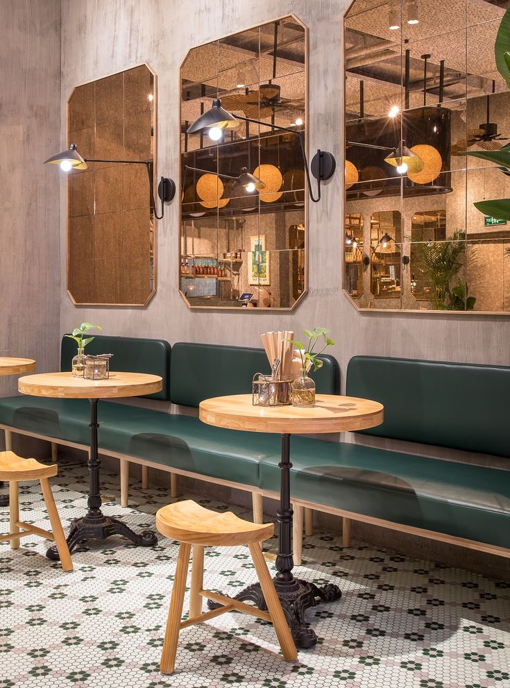 a restaurant with green benches and mirrors on the wall