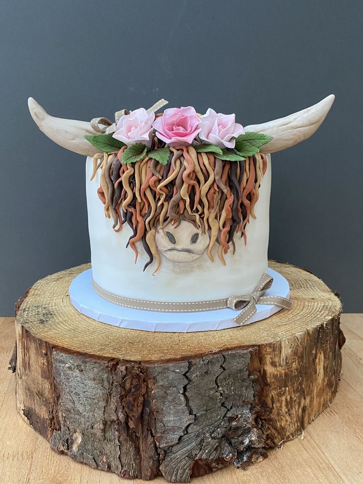 a cake decorated with flowers and horns on top of a tree stump