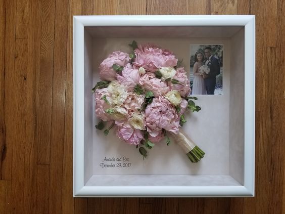 a bouquet of pink flowers in a white frame