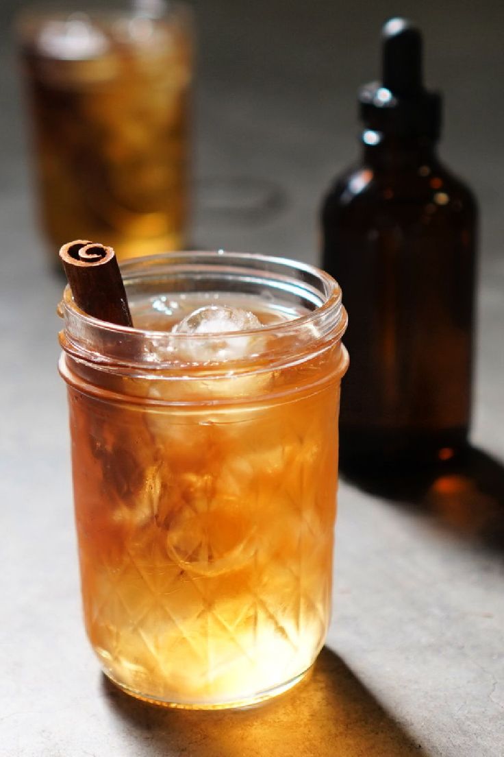 a glass jar filled with liquid next to a brown bottle on top of a table