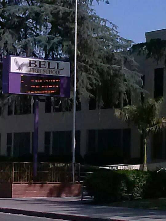 a street sign in front of a building with palm trees on the side of it