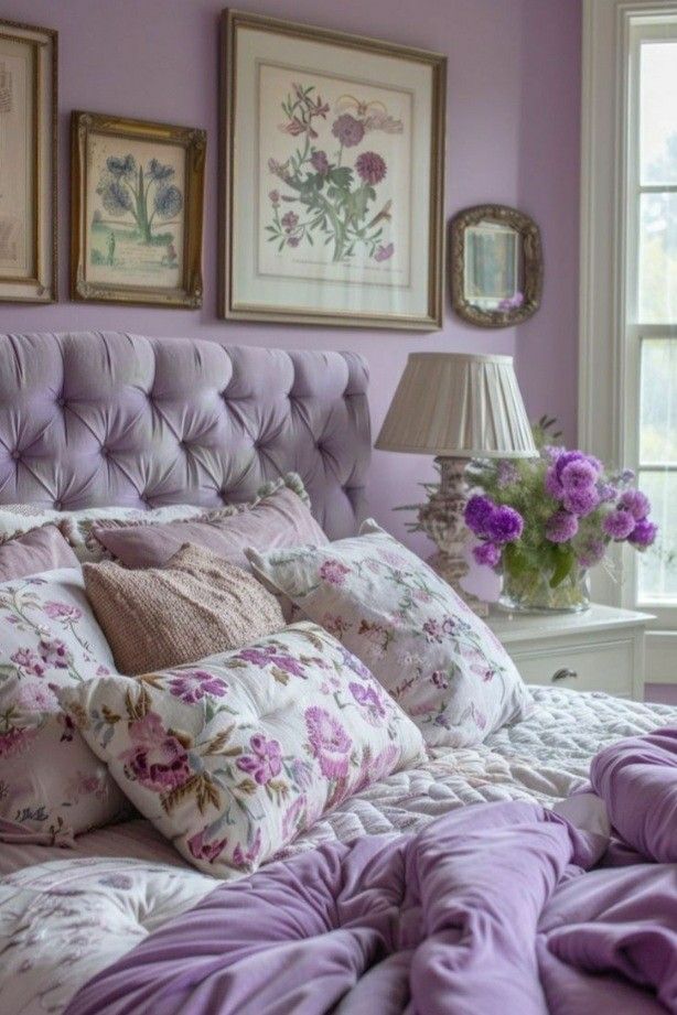 a bed with purple sheets and pillows in a bedroom next to two pictures on the wall