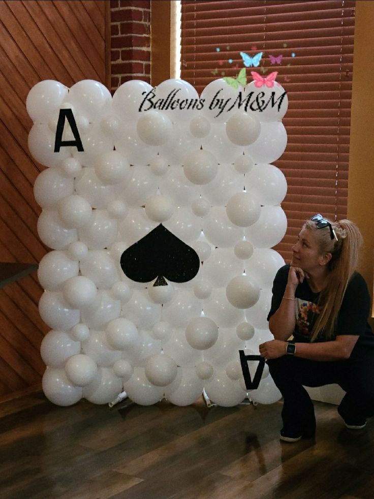 a woman sitting on the floor next to a giant balloon wall with a ace playing card