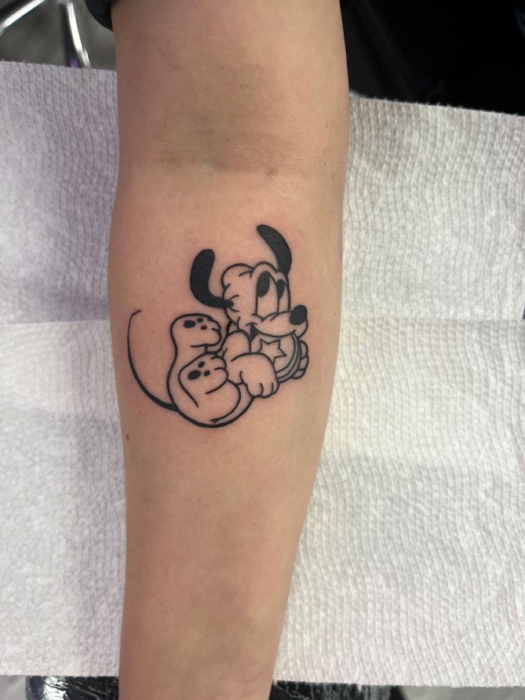 a person with a tattoo on their arm holding onto a stuffed animal in the shape of a dog