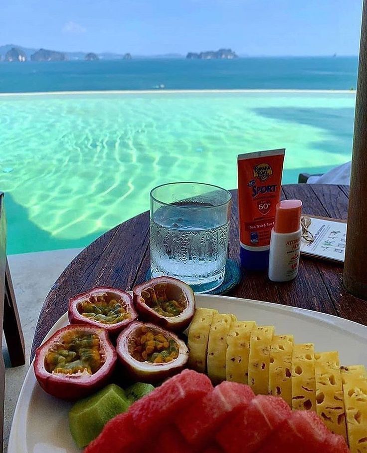 a plate full of fruit and watermelon on a table near an ocean view