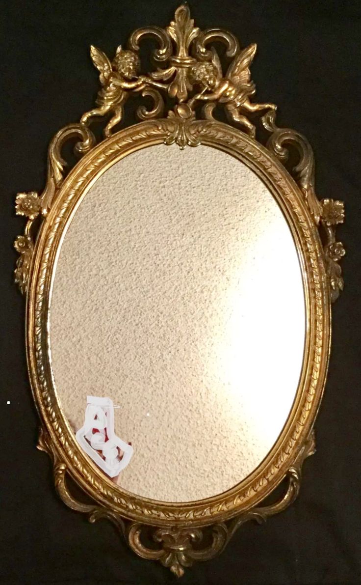 an ornate gold framed mirror with a teddy bear on it's side and the reflection of a white teddy bear