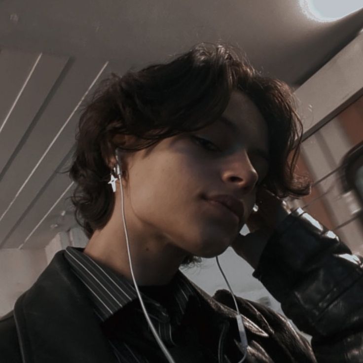 a young man wearing headphones and listening to music on his cell phone while riding in a bus