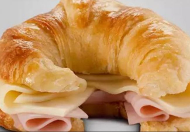 a croissant with ham and cheese on it