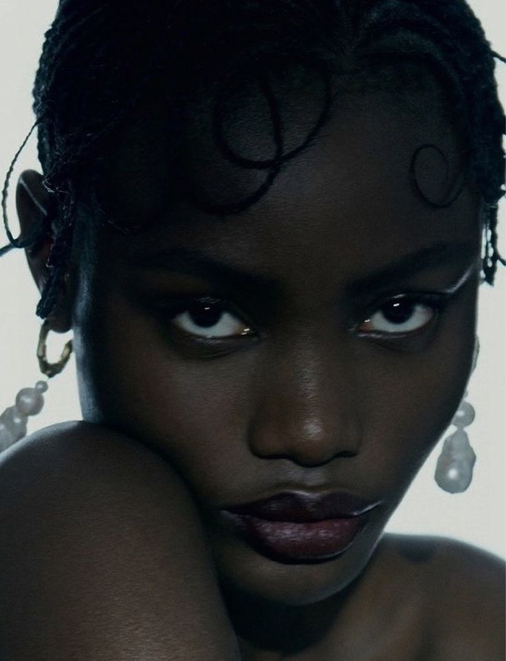 a close up of a person with dark skin and large earrings on her head, looking at the camera