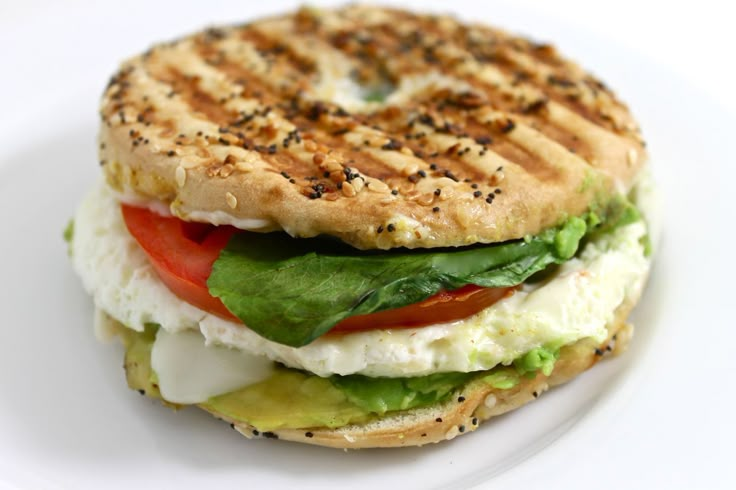 a grilled sandwich with lettuce, tomato and cucumber on a white plate