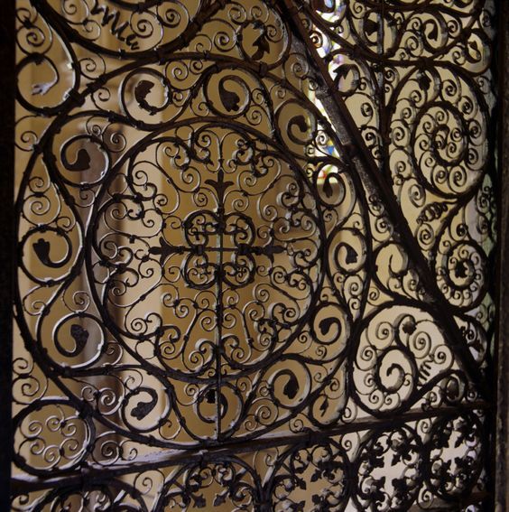 an ornate iron gate with intricate designs on it's sides and the top part of the door