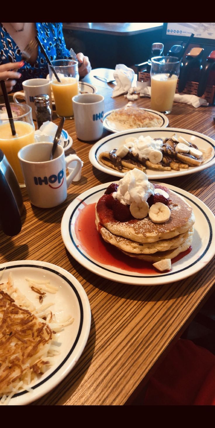 pancakes and other breakfast foods are on the table at an eater's restaurant, with orange juice in the background