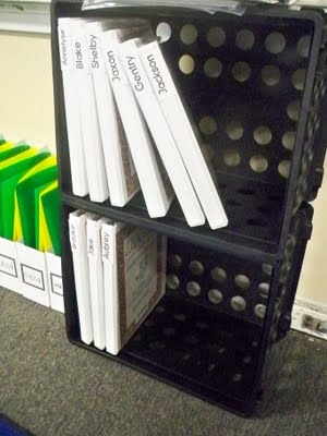 several books are stacked on top of each other in a book case next to a pile of binders