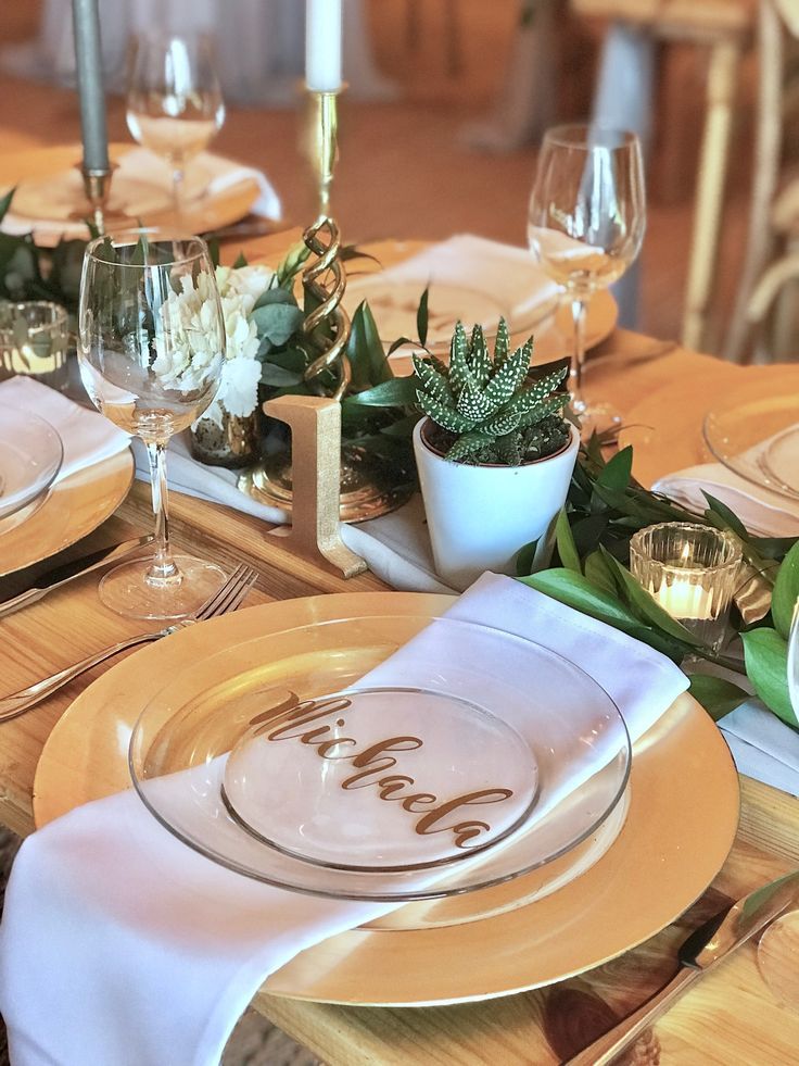 the table is set with white and gold plates, silverware, and succulents