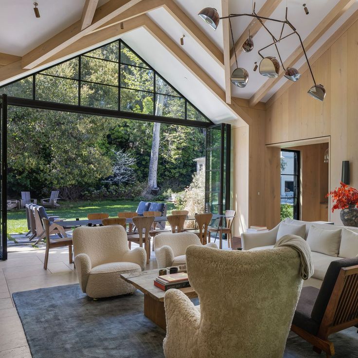 a living room filled with lots of furniture next to a large glass wall window on top of a hard wood floor