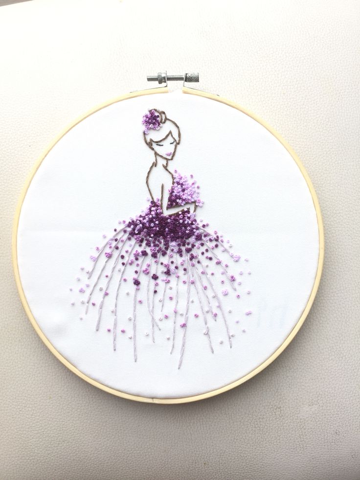 a woman in a purple dress is embroidered on a white wall hanging with beads and thread