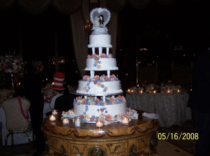 a wedding cake is on display in the middle of a banquet room with candles around it