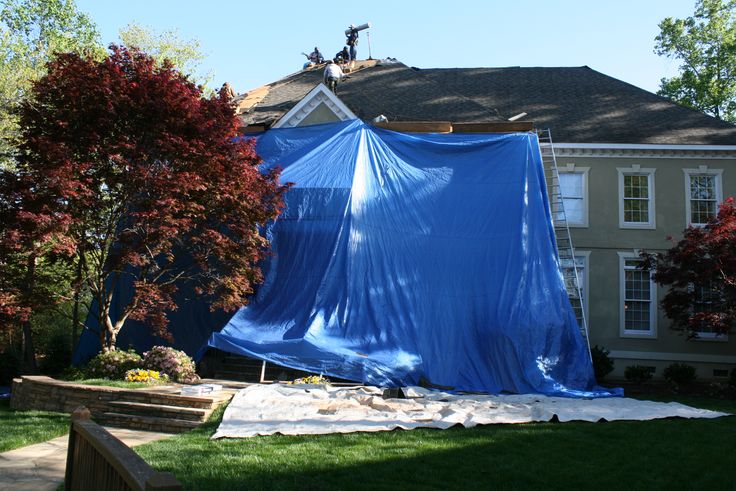 a blue tarp covering a house in the yard