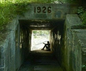 a person sitting in the middle of a tunnel with trees growing on top of it