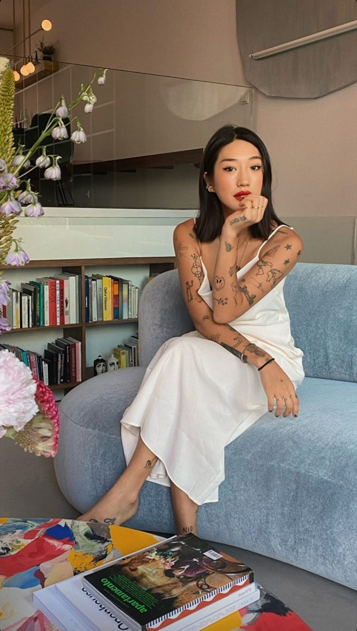 a woman with tattoos sitting on a blue couch