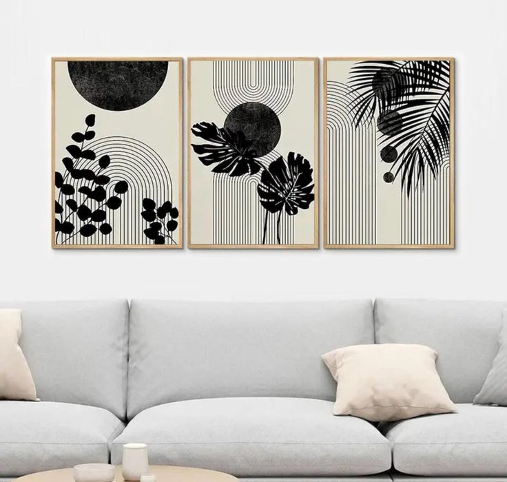 two black and white paintings hanging on the wall next to a couch in a living room