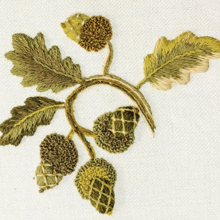 an embroidered piece of art with leaves and acorns