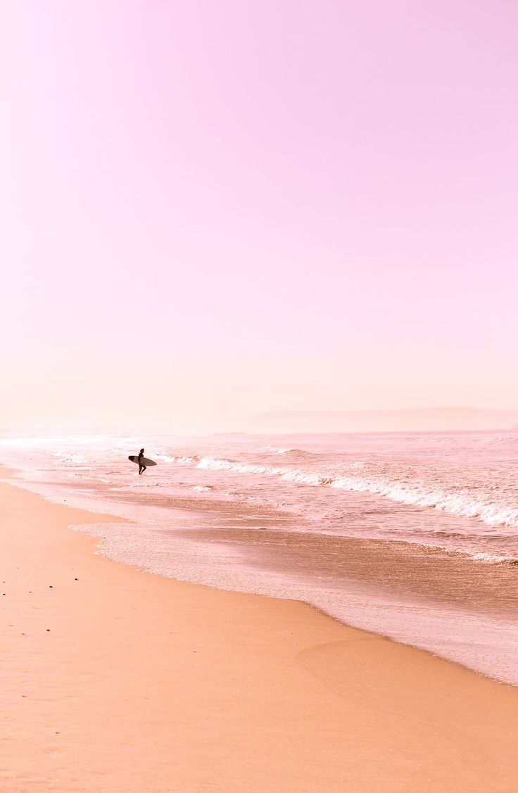 a person walking on the beach with a surfboard