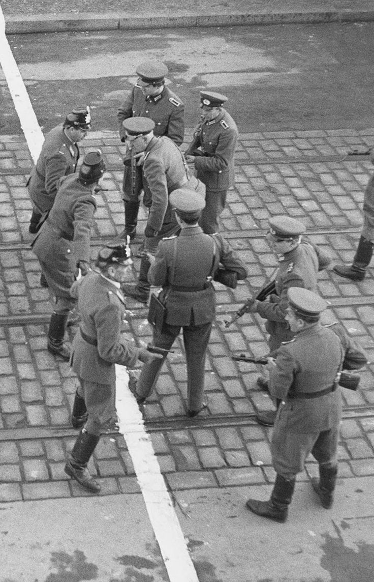 an old black and white photo of men in uniforms talking to each other on the street