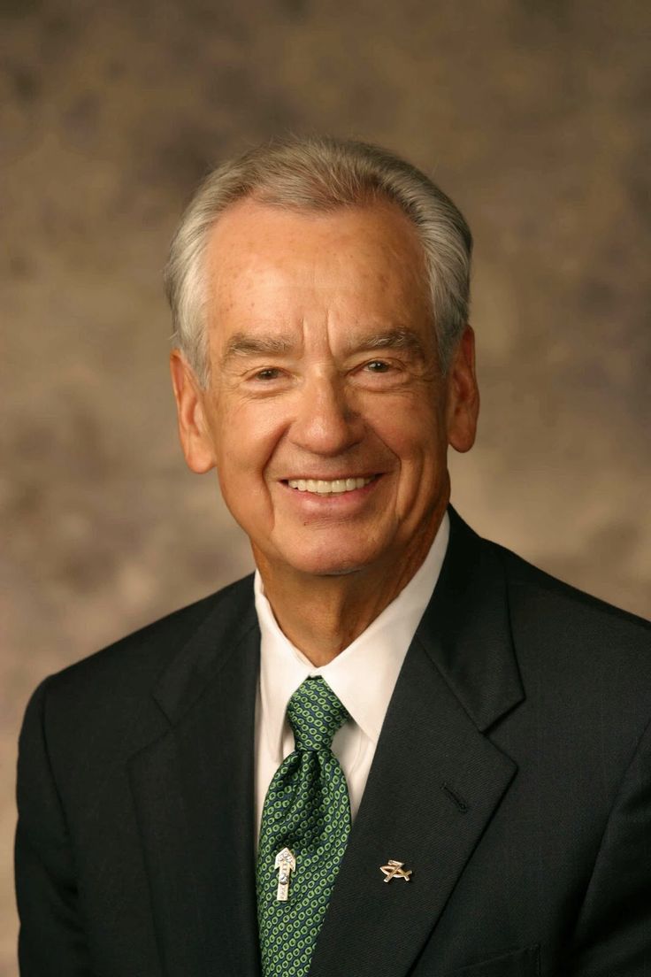 an older man in a suit and tie smiling for the camera with his eyes closed