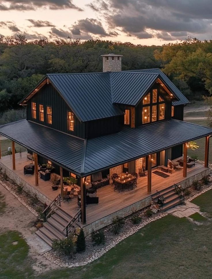 an aerial view of a house with a covered deck and outdoor dining area at dusk