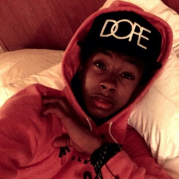 a young man in a red hoodie laying on a bed