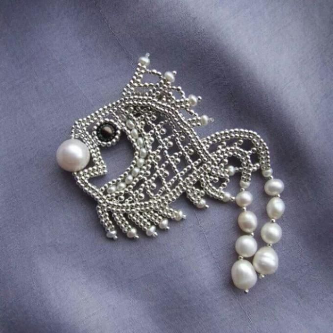 a close up of a brooch with pearls on it