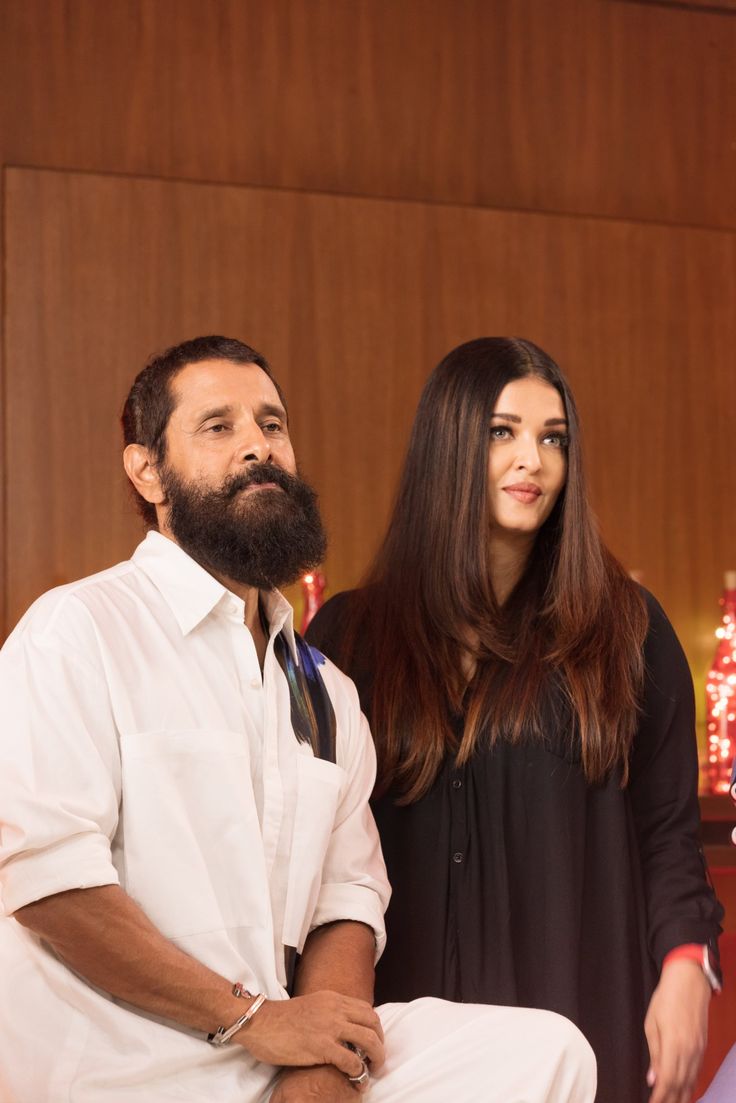 a man and woman standing next to each other in front of a christmas tree with lights on it