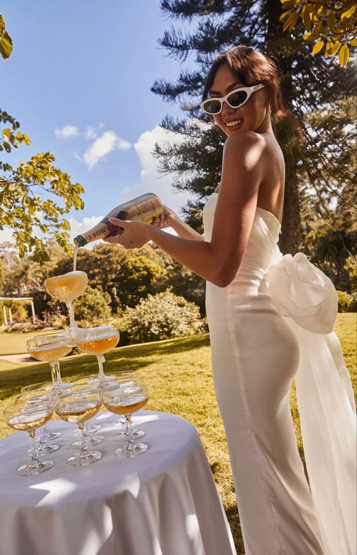 a woman standing in front of a table filled with wine glasses and an open book