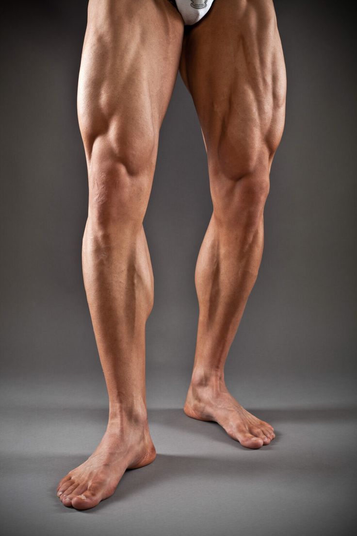 a man's legs with no shirt on and one leg showing, in front of a gray background