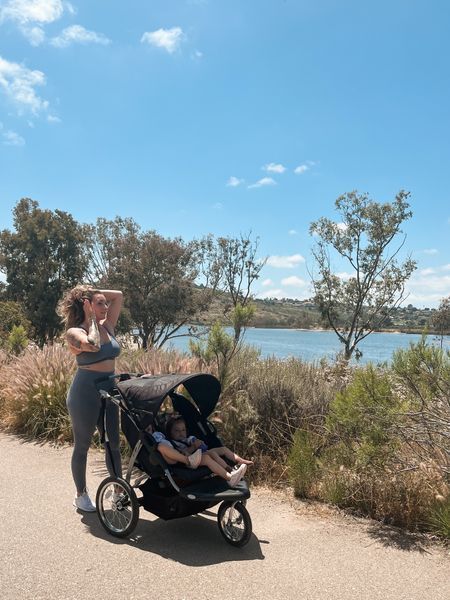 a woman standing next to a baby in a stroller on the side of a road