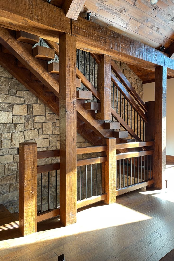 a wooden stair case next to a stone wall and wood flooring in a home