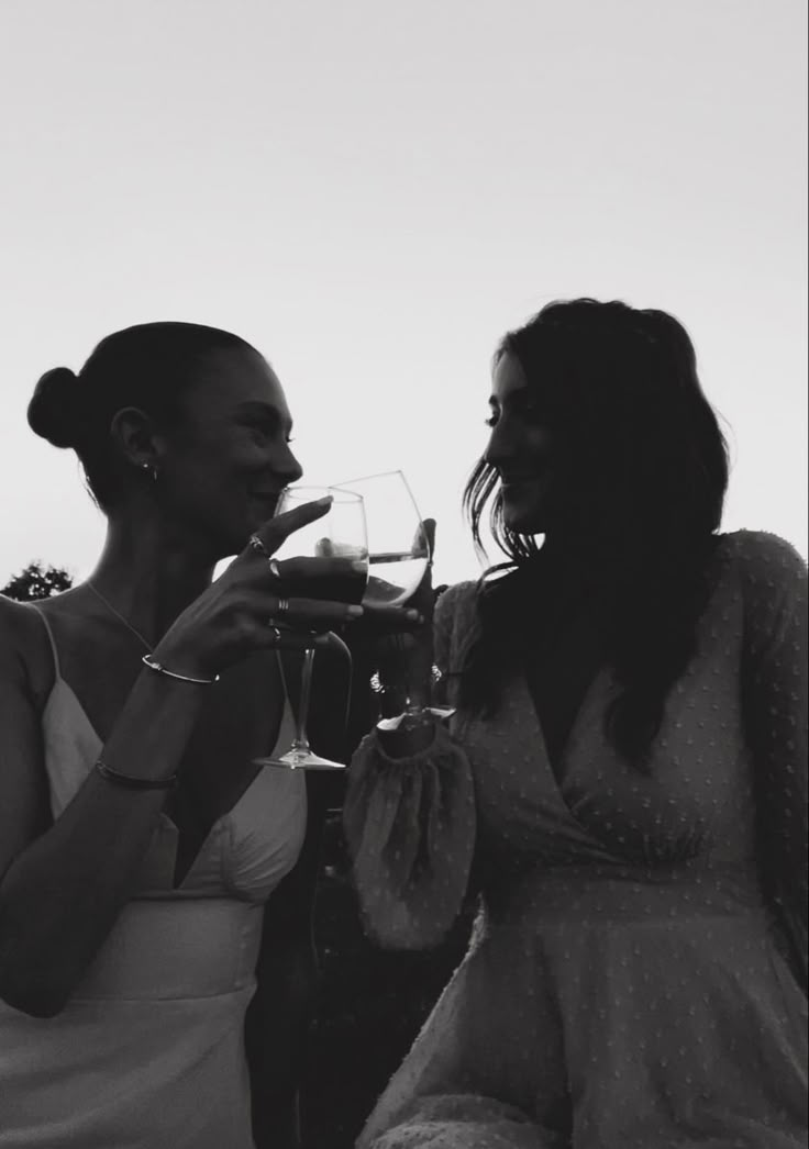 two women standing next to each other drinking wine