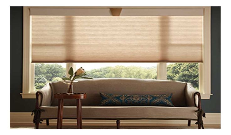 a living room filled with furniture and windows covered in roman blind shades on top of them